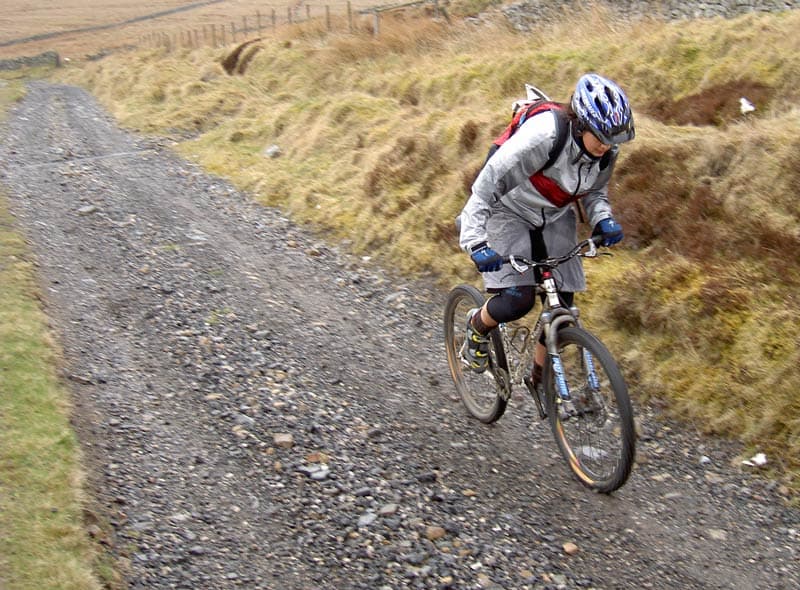 Illustrative photo of a mountain biker climbing an unpaved track; not a photo of this venue.