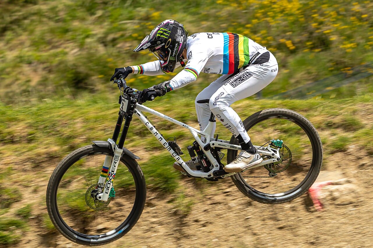 Illustrative photo of a downhill mountain-bike racer on a dirt trail; not a photo of this venue.